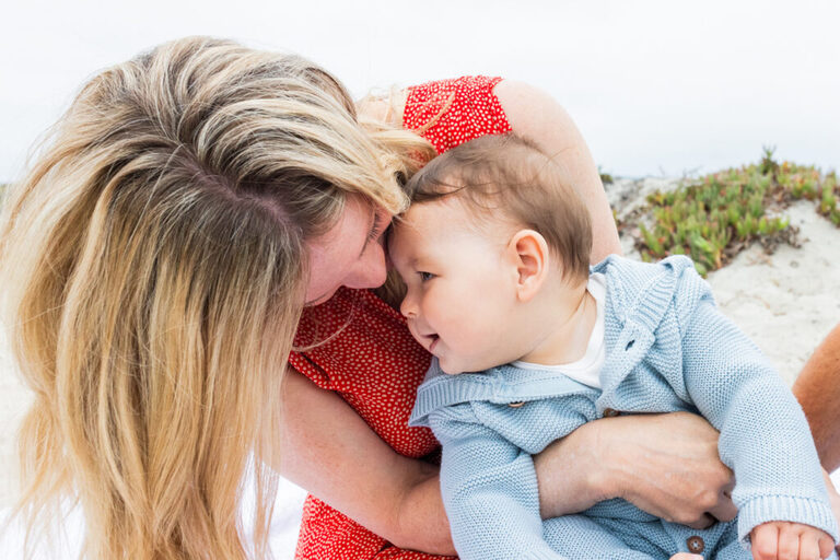 Parents and baby pose with their dog during a Coronado Beach family photography session